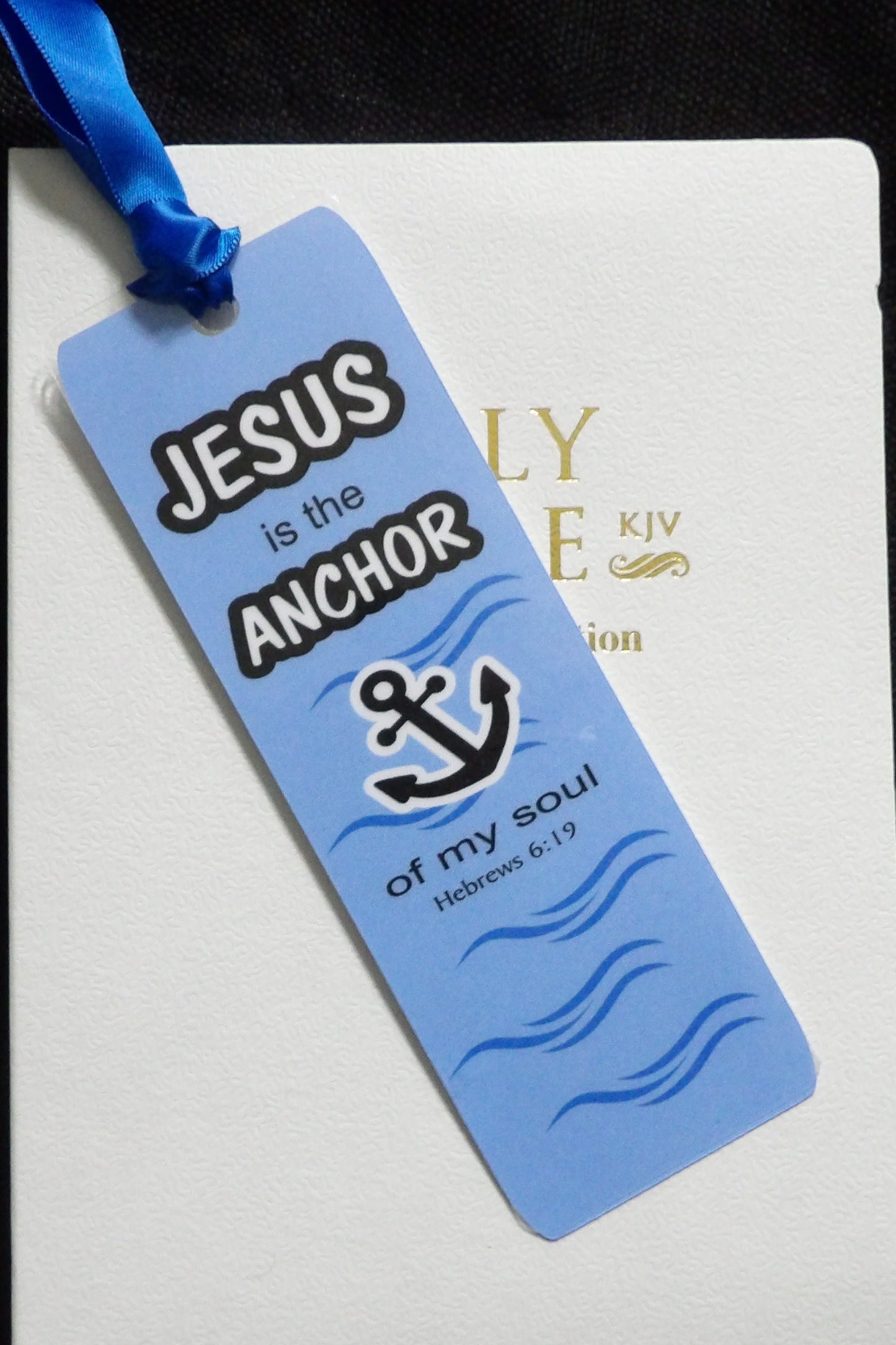 Blue bookmark with 'Jesus is the Anchor of my soul' text on a white notebook with gold text.